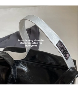 Detail of glossy black Boston bag featuring shiny silver textured shoulder strap and zipper