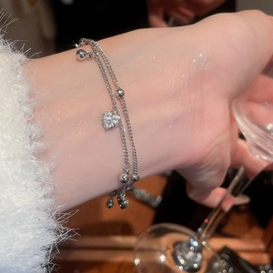 Close-up of a double-layered 18k gold plated bracelet with a sparkling zircon heart pendant