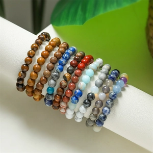 Detail of assorted natural stone planet bracelets featuring colorful beads on a white stand