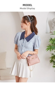 Detail of pink embossed leather handbag with heart patterns and gold metal chain strap