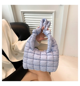 Close-up of light blue quilted puffer shoulder bag with a stylish knotted handle detail