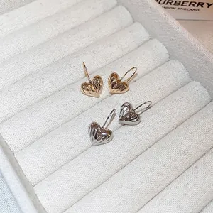 Minimalist gold and silver heart earrings with radiant texture in a jewelry box