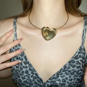 Polished gold heart pendant choker necklace worn by a model for a stylish metal look