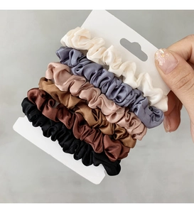 Dettaglio del set di 6 elastici per capelli in raso in colori neutri su cartone