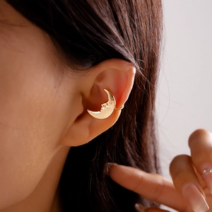 Close-up of golden crescent moon ear cuff with vintage face relief on female model