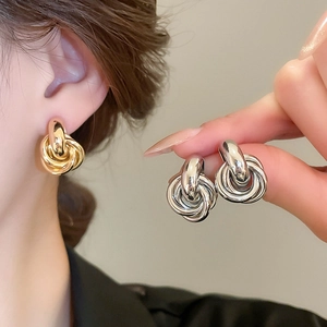 Detail von verdrehten Knoten-Ohrringen in Gold und Silber am Model mit Silbernadel