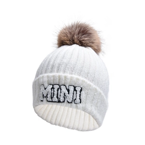 Dettaglio del berretto in maglia bianco con ricamo MINI e pompon marrone soffice