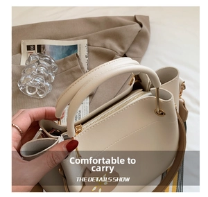 Detail view of the comfortable cream tote bag handle with elegant flower charm and metal hardware