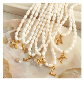 Macro shot of freshwater pearl necklace with gold plated alphabet pendants on shell