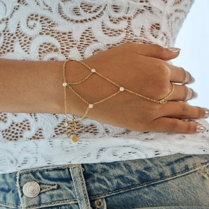 Détail d'un bracelet bague doré orné de zircons et d'une chaîne à pampilles délicate