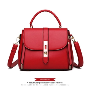 Detail view of red faux leather tote bag with gold buckle and decorative side zippers