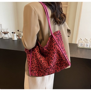 Close-up of leopard print tote bag with pink leather edges on a model in a cafe