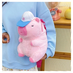 Detailed view of plush pink pig crossbody bag with blue C cap and adjustable shoulder strap