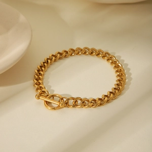 Close-up of a polished 18K gold Cuban chain bracelet featuring a stylish OT clasp
