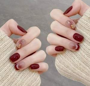 Detail of short square press-on nails in burgundy and nude gradient with gold foil flakes