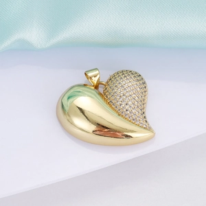 Close-up of heart-shaped gold pendant with sparkling crystals on light blue silk fabric