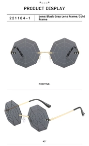Detail of octagonal rimless sunglasses with gold spider web metal frame and grey lenses