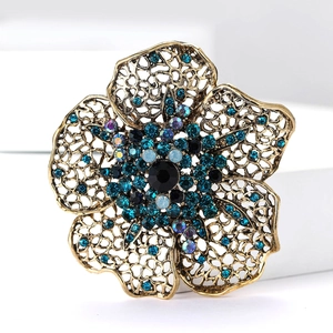 Macro detail of vintage floral brooch with blue rhinestones and gold hollow petals
