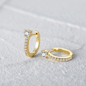 Macro shot of S925 silver gold curved wave hoop earrings with pavé cubic zirconia
