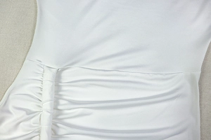 Nahaufnahme der gerafften Stoffstruktur eines weißen Bodycon-Kleids mit Falten-Details