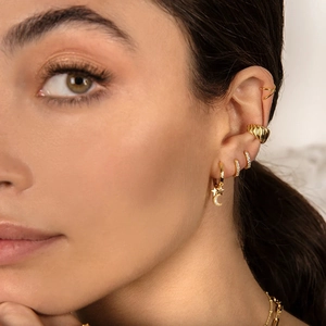 Close-up of gold S925 silver hoop earrings with star and moon charms on model ear