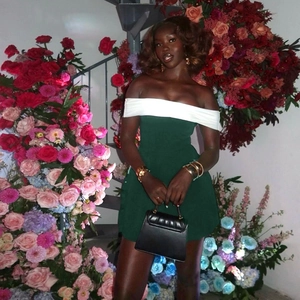 Elegant off-shoulder bodycon dress in dark green and white with a chic black handbag