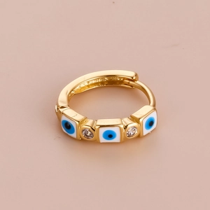Bohemian gold hoop earring with blue evil eye charm and clear zircon on pink background