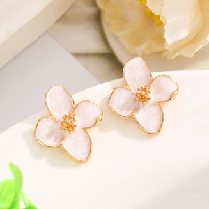 Macro detail of four-petal flower earrings with soft pink enamel and gold-plated edges