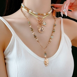 Close-up of bohemian layered beaded necklace with butterfly and leaf pendants on model