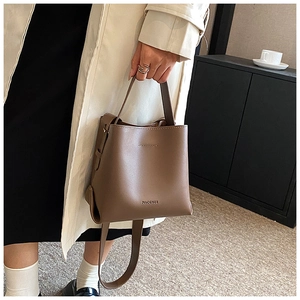 Detail of vintage brown leather bucket bag with top handle and brand logo MACGNEE