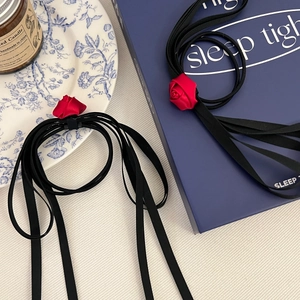 Detailed close-up of a handmade red 3D satin rose with long black ribbon ties