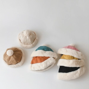 Flat lay of colorful toddler winter suede hats with white pom-poms and plush lining