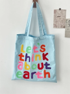 Detail of colorful towel embroidery slogan Let's think about earth on blue canvas bag