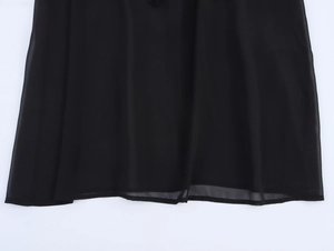 Gros plan sur l'ourlet de la robe en mousseline noire montrant la texture légère du tissu
