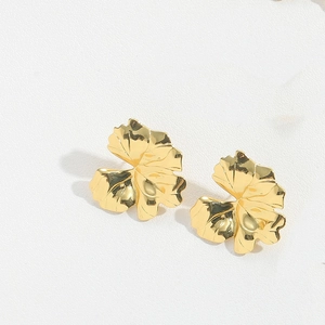 Macro shot of gold-plated leaf earrings with detailed vein texture and high-polish finish