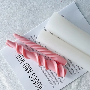 Detail shot of pink spiral taper candles and white block candles on a clean white fabric