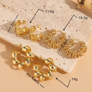 Three sizes of 14K gold plated twist C-shape hoop earrings with zircon on stone background