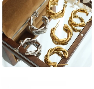 Detail showing high-gloss gold and silver 18K plated C-shaped twisted hoop earrings