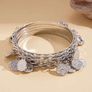 Detail of silver layered bracelet set featuring vintage coin pendants and wavy textures