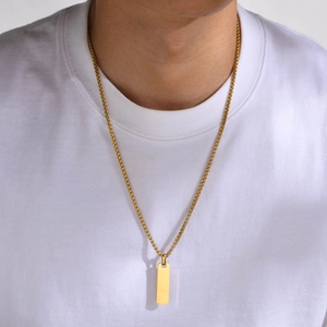 Close-up of a minimalist gold rectangular pendant and box chain worn on a white neck