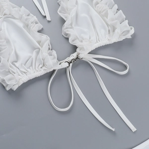 Detail of white bikini top with ruffled edges and metallic hardware buckle closure