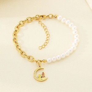 Detail of gold chain and pearl bracelet featuring a moon pendant with colorful enamel