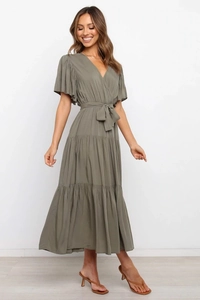 Detalle de vestido largo verde oliva con escote en V, falda escalonada y lazo en cintura