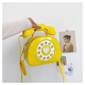 Detail of yellow retro telephone crossbody bag featuring rotary dial and handset handle