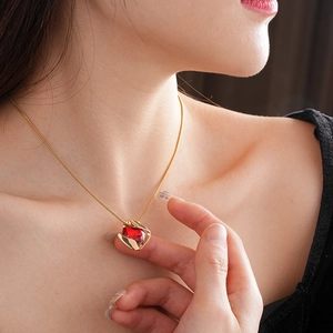 Close-up of a model wearing a gold necklace with a square-cut red gemstone pendant