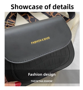 Detail of black crossbody bag with crocodile texture and gold FASHION & BAGS lettering