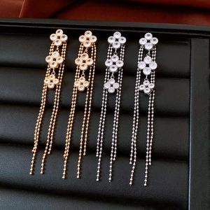 Macro detail of 18K gold plated floral tassel earrings with zircon inlays and sleek chains