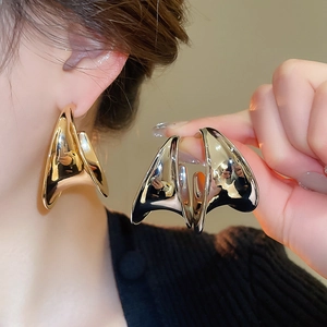 Detailed view of chunky C-shape metallic earrings in gold and silver finish with high shine