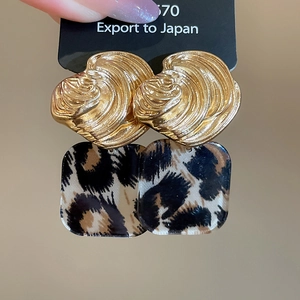 Macro detail of vintage acrylic square earrings with leopard print and gold spiral texture