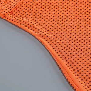 Gros plan des strass orange sur le tissu froncé pour une robe de soirée chic